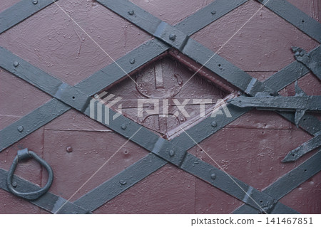 Medieval style black iron strap hinge on old painted wooden door close up Medieval style black iron strap hinge on old painted wooden door close up 141467851