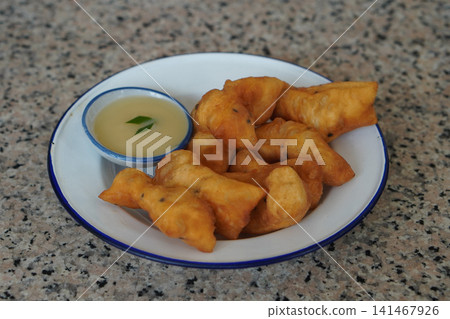 hot four pieces of patongko and condensed milk in a ceramic cup, placed on a white and blue enamel plate on a marble surface background, food, dessert, copy space hot four pieces of patongko and condensed milk in a ceramic cup, placed on a white and blue enamel plate on a marble surface background, food, dessert, copy space 141467926