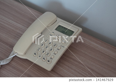 top view A white office phone on a wooden desk, white cement wall background, object, decor, technology, electric, copy space. top view A white office phone on a wooden desk, white cement wall background, object, decor, technology, electric, copy space. 141467929