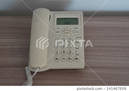 closeup A white plastic office phone on a wooden floor, white cement wall background, object, decor, technology, electric, copy space. closeup A white plastic office phone on a wooden floor, white cement wall background, object, decor, technology, electric, copy space. 141467939