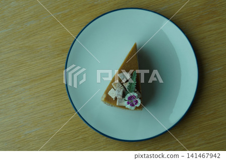 closeup cake Khanom Mo Kaeng, garnished with purple and white flowers and green leaves, topped with taro slices, and served on a white and blue color ceramic plate, on wooden floor background, , food, closeup cake Khanom Mo Kaeng, garnished with purple and white flowers and green leaves, topped with taro slices, and served on a white and blue color ceramic plate, on wooden floor background, , food, 141467942