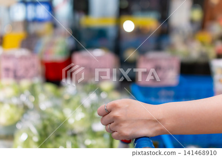 A woman's hands and shopping cart as she buys daily necessities and groceries. A woman's hands and shopping cart as she buys daily necessities and groceries. 141468910