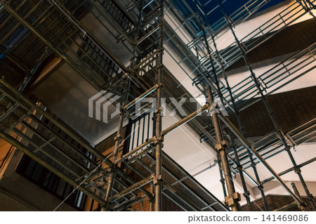 Metal scaffolding erected during large-scale renovation work on an apartment building at night. 141469086