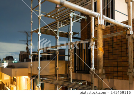 Night view of an apartment building undergoing large-scale repair work to address aging infrastructure. Night view of an apartment building undergoing large-scale repair work to address aging infrastructure. 141469116