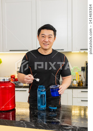 Asian man mixing supplement powder in shaker bottle shaking electrolyte recovery drink at home gym Asian man mixing supplement powder in shaker bottle shaking electrolyte recovery drink at home gym 141469364