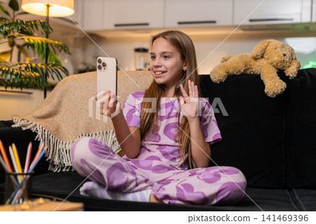 Teenager girl video call on smartphone tells school story to friend lively gesture smile active chat Teenager girl video call on smartphone tells school story to friend lively gesture smile active chat 141469396
