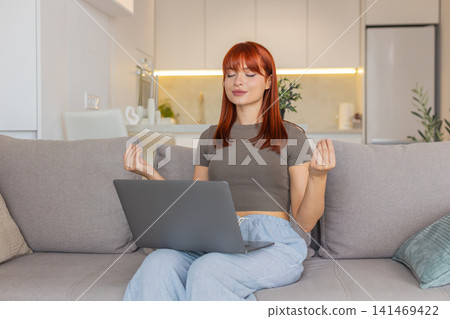 Young woman takes break from laptop work does meditation deep breathing and tries to calm down focus 141469422
