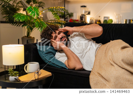 Arabian man lies with strong headache holds head at temple closes eyes feels pain needs rest tonight Arabian man lies with strong headache holds head at temple closes eyes feels pain needs rest tonight 141469463