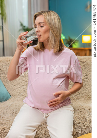 Pregnant woman drinking pure water hand on belly showing hydration importance for healthy pregnancy Pregnant woman drinking pure water hand on belly showing hydration importance for healthy pregnancy 141469474