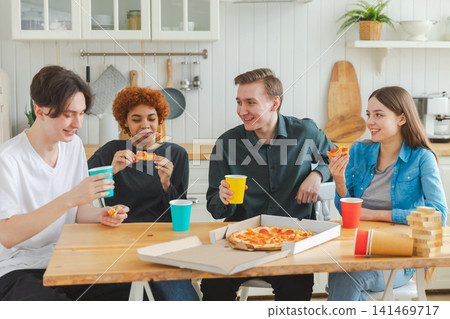 Home party. Overjoyed diverse friends eating ordered pizza for home party. Happy group multiracial young buddies enjoying spending free weekend time together having fun laughing joking communicating Home party. Overjoyed diverse friends eating ordered pizza for home party. Happy group multiracial young buddies enjoying spending free weekend time together having fun laughing joking communicating 141469717