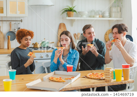 Home party. Overjoyed diverse friends eating ordered pizza for home party. Happy group multiracial young buddies enjoying spending free weekend time together having fun laughing joking communicating Home party. Overjoyed diverse friends eating ordered pizza for home party. Happy group multiracial young buddies enjoying spending free weekend time together having fun laughing joking communicating 141469719