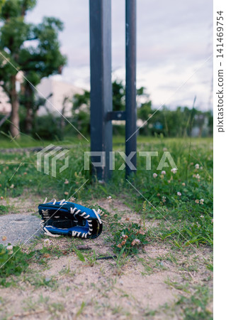 公園草坪上放著一隻藍黑相間的棒球手套。 公園草坪上放著一隻藍黑相間的棒球手套。 141469754