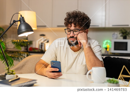 Arabian man bored scrolls smartphone news at night stressed demotivated sighs needs break from news Arabian man bored scrolls smartphone news at night stressed demotivated sighs needs break from news 141469783