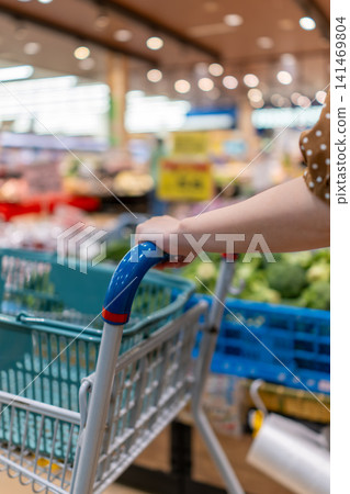 Hands of shoppers searching for products in a brightly lit supermarket 141469804