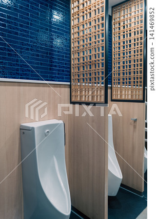 A modern men's restroom featuring wooden latticework and blue tiles. A modern men's restroom featuring wooden latticework and blue tiles. 141469852