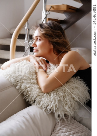 Home relaxation. Peaceful mood. Dreamy elegant female on comfortable soft sofa enjoying daily quiet atmosphere modern interior. Home relaxation. Peaceful mood. Dreamy elegant female on comfortable soft sofa enjoying daily quiet atmosphere modern interior. 141469891