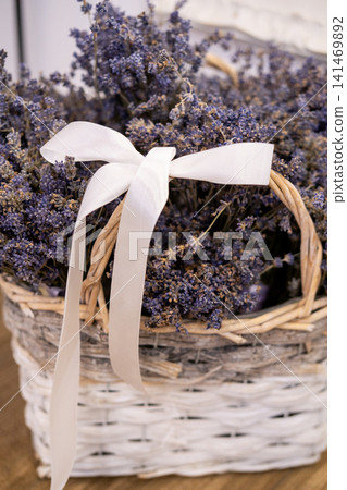 Lavender basket. Floral composition. Dried garden purple flowers white satin ribbon for rustic home gift aesthetic decoration. Lavender basket. Floral composition. Dried garden purple flowers white satin ribbon for rustic home gift aesthetic decoration. 141469892