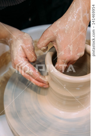 Ceramics inspiration. Creative potter. Unrecognizable specialist woman hands working with artisan pot using wheel in workplace. Ceramics inspiration. Creative potter. Unrecognizable specialist woman hands working with artisan pot using wheel in workplace. 141469954