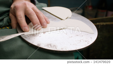 Professional artisan. Cobbler workplace. Unrecognizable expert hands using metal knife for shoe trimming leather material in store. Professional artisan. Cobbler workplace. Unrecognizable expert hands using metal knife for shoe trimming leather material in store. 141470020