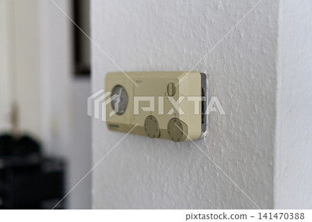 Vintage analog thermostat mounted on a white textured wall Vintage analog thermostat mounted on a white textured wall 141470388