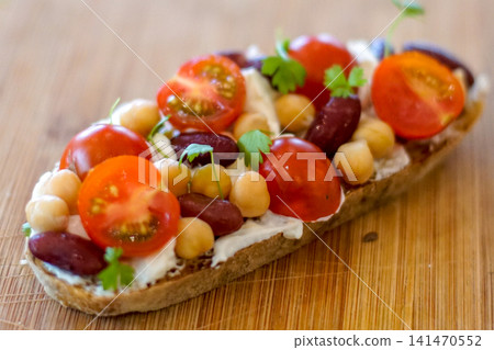 Healthy open-faced sandwich topped with cherry tomatoes, chickpeas, kidney beans, fresh herbs, and cream cheese on artisan bread. Homemade brunch, vegetarian meal, and clean eating concept. Healthy open-faced sandwich topped with cherry tomatoes, chickpeas, kidney beans, fresh herbs, and cream cheese on artisan bread. Homemade brunch, vegetarian meal, and clean eating concept. 141470552
