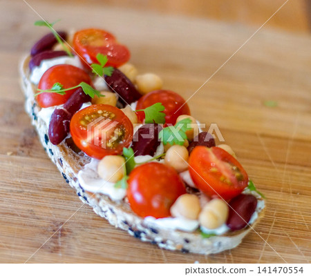 Healthy open-faced sandwich topped with cherry tomatoes, chickpeas, kidney beans, fresh herbs, and cream cheese on artisan bread. Homemade brunch, vegetarian meal, and clean eating concept. Healthy open-faced sandwich topped with cherry tomatoes, chickpeas, kidney beans, fresh herbs, and cream cheese on artisan bread. Homemade brunch, vegetarian meal, and clean eating concept. 141470554