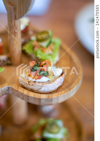 Close Up Gourmet Canape with Fresh Tomato Herbs and Cheese on Artisan Bread Served on Rustic Wooden Tiered Stand Elegant Finger Food Appetizer for Cafe Catering and Fine Dining Close Up Gourmet Canape with Fresh Tomato Herbs and Cheese on Artisan Bread Served on Rustic Wooden Tiered Stand Elegant Finger Food Appetizer for Cafe Catering and Fine Dining 141470565