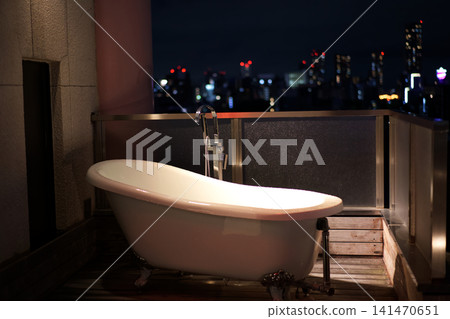 Luxury hotel balcony with a view of the city lights and an outdoor clawfoot bathtub Luxury hotel balcony with a view of the city lights and an outdoor clawfoot bathtub 141470651