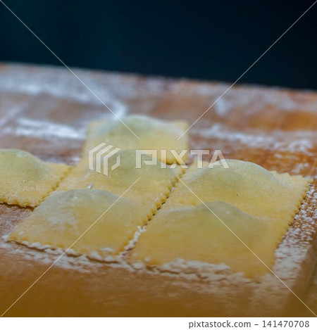 Fresh Handmade Ravioli on Floured Wooden Board, Traditional Italian Fresh Pasta Preparation, Artisan Homemade Cuisine, Rustic Cooking Process and Fresh Dough Concept Fresh Handmade Ravioli on Floured Wooden Board, Traditional Italian Fresh Pasta Preparation, Artisan Homemade Cuisine, Rustic Cooking Process and Fresh Dough Concept 141470708