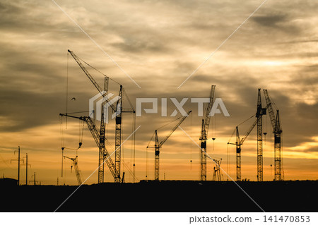 Construction cranes silhouettes at sunset sky Construction cranes silhouettes at sunset sky 141470853