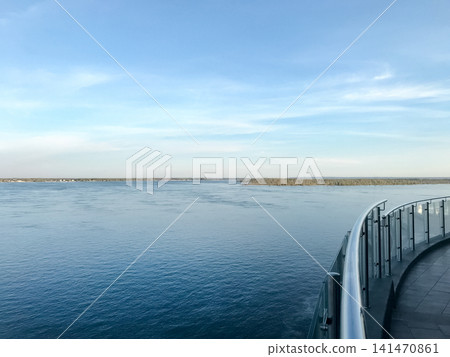 A serene horizon featuring a calm river and a distant shore under a blue sky. The Volga River. A serene horizon featuring a calm river and a distant shore under a blue sky. The Volga River. 141470861
