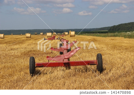 Header trailers in harvested wheat field with round hay bales during seasonal farming operations Header trailers in harvested wheat field with round hay bales during seasonal farming operations 141470898