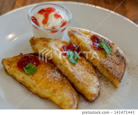 Golden French Toast with Strawberry Sauce, Vanilla Ice Cream, Powdered Sugar and Fresh Mint on a Plate, Sweet Breakfast or Brunch Dessert Golden French Toast with Strawberry Sauce, Vanilla Ice Cream, Powdered Sugar and Fresh Mint on a Plate, Sweet Breakfast or Brunch Dessert 141471441