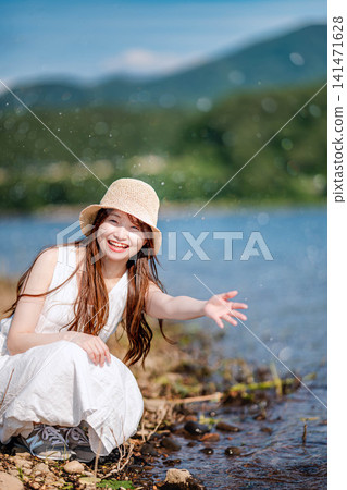 一位女子在湖邊水中快樂地玩耍。 一位女子在湖邊水中快樂地玩耍。 141471628