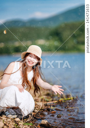 夏日里,一位女子在水邊嬉戲玩耍,臉上洋溢著笑容。 夏日里,一位女子在水邊嬉戲玩耍,臉上洋溢著笑容。 141471633
