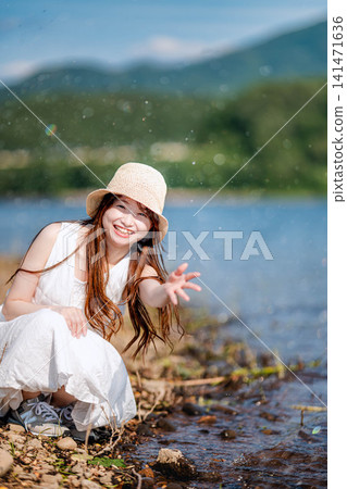 一位戴著草帽的女子麵帶微笑,撫摸著湖水。 一位戴著草帽的女子麵帶微笑,撫摸著湖水。 141471636