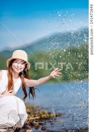 湖水濺到一位穿著白色洋裝的女子身上,她笑了起來。 湖水濺到一位穿著白色洋裝的女子身上,她笑了起來。 141471649