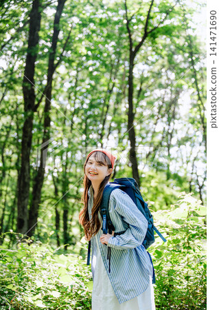 陽光斑駁的森林中,一位戴著紅色帽子的女子回頭望去。 陽光斑駁的森林中,一位戴著紅色帽子的女子回頭望去。 141471690