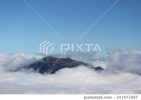A magnificent mountain landscape of Mt. Kamegamori, set against a vast sea of clouds and a clear blue sky, as seen from Mt. Ishizuchi in Ehime Prefecture. A magnificent mountain landscape of Mt. Kamegamori, set against a vast sea of clouds and a clear blue sky, as seen from Mt. Ishizuchi in Ehime Prefecture. 141471807