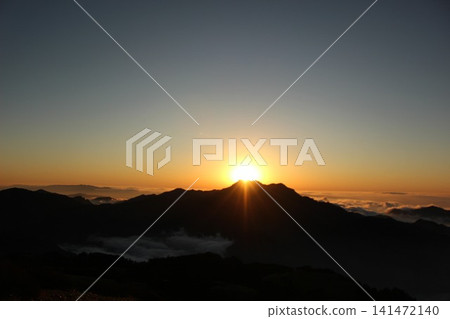 A fantastical sunset viewed from Mt. Kamegamori in the Ishizuchi mountain range of Ehime Prefecture: A sea of clouds in the magic hour and the silhouette of Mt. Ishizuchi illuminated by the setting sun. A fantastical sunset viewed from Mt. Kamegamori in the Ishizuchi mountain range of Ehime Prefecture: A sea of clouds in the magic hour and the silhouette of Mt. Ishizuchi illuminated by the setting sun. 141472140