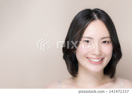 照片中,一位美麗的日本女子在粉米色的背景下,展現出她無瑕的肌膚和自然的妝容,特寫鏡頭中,她面帶微笑,直視鏡頭。 照片中,一位美麗的日本女子在粉米色的背景下,展現出她無瑕的肌膚和自然的妝容,特寫鏡頭中,她面帶微笑,直視鏡頭。 141472157