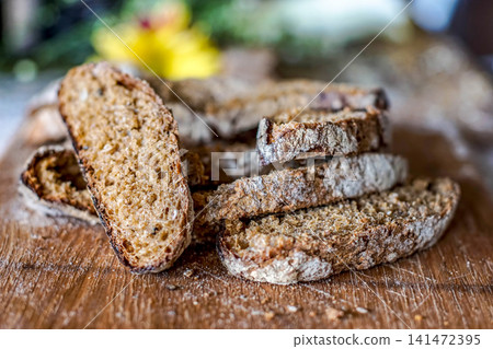 Rustic Artisan Whole Grain Bread Slices on Wooden Cutting Board, Homemade Multigrain Loaf, Fresh Bakery Product, Healthy Breakfast, Organic Baking, Close Up Food Photography Rustic Artisan Whole Grain Bread Slices on Wooden Cutting Board, Homemade Multigrain Loaf, Fresh Bakery Product, Healthy Breakfast, Organic Baking, Close Up Food Photography 141472395