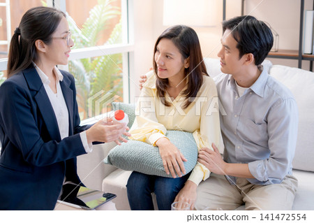 Asian couple in living room consulting with psychologist for marriage therapy. Asian couple in living room consulting with psychologist for marriage therapy. 141472554