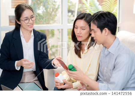 Asian young couple on sofa consulting with psychologist in living room at home. Asian young couple on sofa consulting with psychologist in living room at home. 141472556