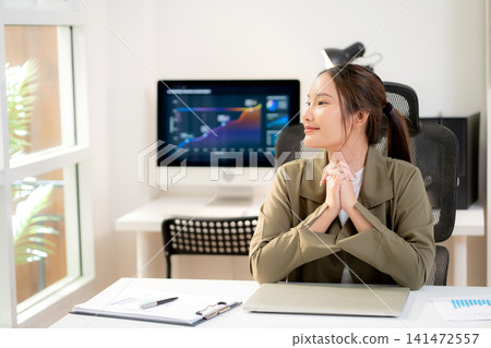 Asian young businesswoman sitting and working at modern office desk with laptop computer. Asian young businesswoman sitting and working at modern office desk with laptop computer. 141472557