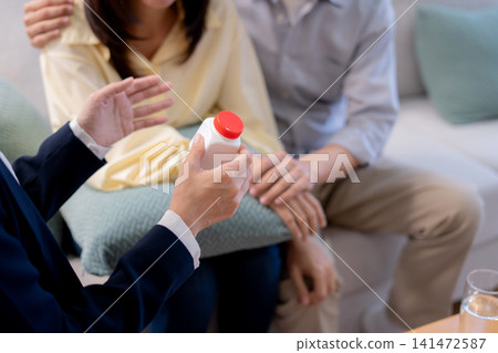 Asian young couple on sofa consulting with psychologist in living room at home. Asian young couple on sofa consulting with psychologist in living room at home. 141472587
