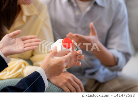 Asian young couple on sofa consulting with psychologist in living room at home. Asian young couple on sofa consulting with psychologist in living room at home. 141472588