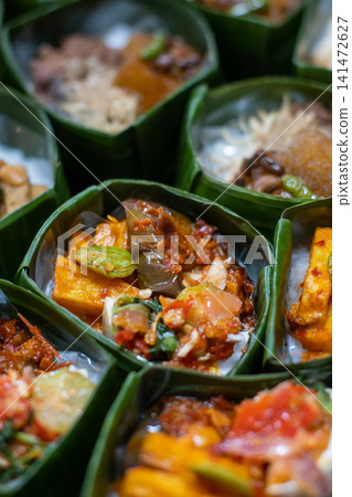 Traditional Indonesian Rice Meal in Banana Leaf Takir with Spicy Tofu, Sambal and Assorted Vegetables, Authentic Nusantara Cuisine, Eco Friendly Food Presentation Traditional Indonesian Rice Meal in Banana Leaf Takir with Spicy Tofu, Sambal and Assorted Vegetables, Authentic Nusantara Cuisine, Eco Friendly Food Presentation 141472627