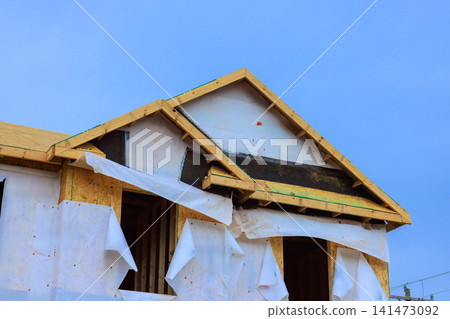 Workers are building wood structure using protective plastic sheeting at construction site 141473092