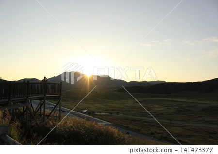 A scene of the sunrise over Kusasenrigahama in Aso City, Kumamoto Prefecture, featuring a vast grassland and pond bathed in the morning sun, and Mount Aso Nakadake with its rising plume of smoke. A scene of the sunrise over Kusasenrigahama in Aso City, Kumamoto Prefecture, featuring a vast grassland and pond bathed in the morning sun, and Mount Aso Nakadake with its rising plume of smoke. 141473377